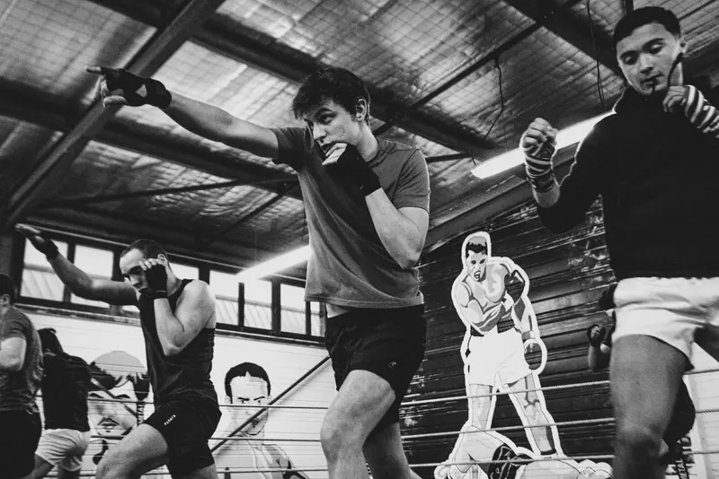 Un boxeur en garde haute au Boxing Center Ramonville, devant la fresque du club.
