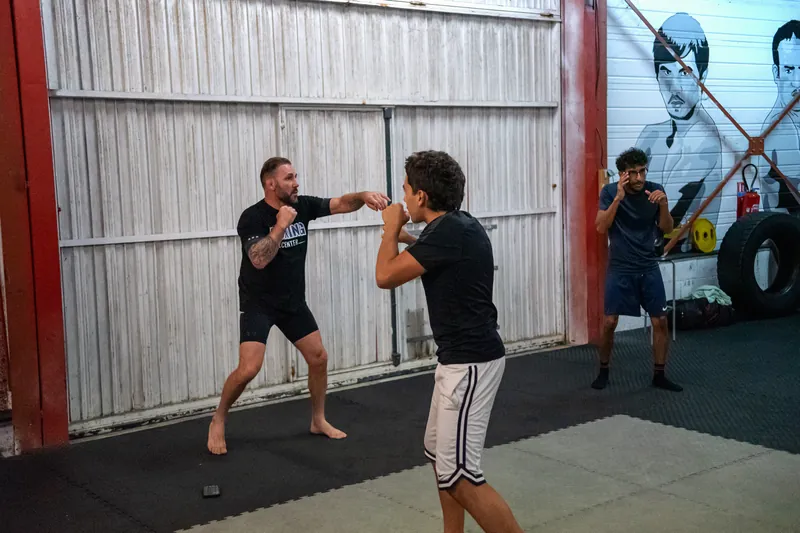 Un coach tient les paos face à un débutant, sur le tatami du Boxing Center Ramonville