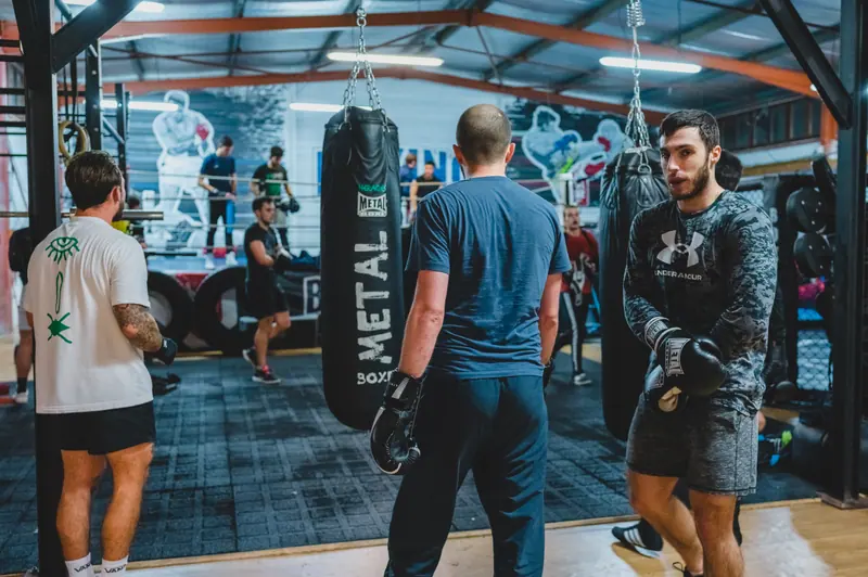 Deux pratiquants devant la ligne de sacs lourds du Boxing Center Ramonville, sous la charpente.